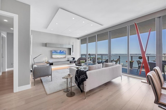 living area with recessed lighting, expansive windows, baseboards, and light wood finished floors