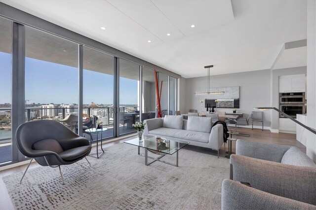 living room featuring recessed lighting, expansive windows, baseboards, and wood finished floors