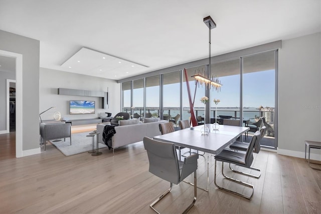 dining area with floor to ceiling windows, baseboards, an inviting chandelier, and wood finished floors