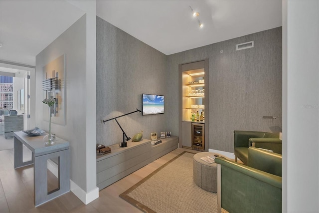 living area with wallpapered walls, wine cooler, visible vents, and an accent wall