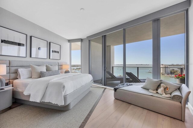 bedroom featuring floor to ceiling windows, multiple windows, wood finished floors, and access to outside