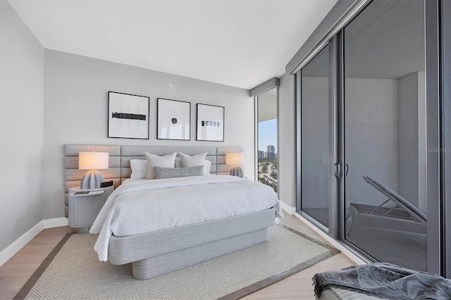 bedroom with expansive windows, baseboards, and light wood-style floors