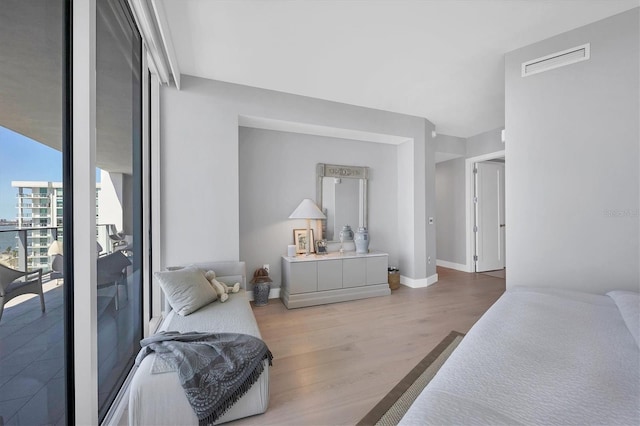 bedroom with visible vents, baseboards, and wood finished floors