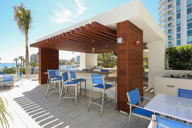 view of patio featuring a view of city, outdoor dry bar, a pergola, a grill, and outdoor dining area