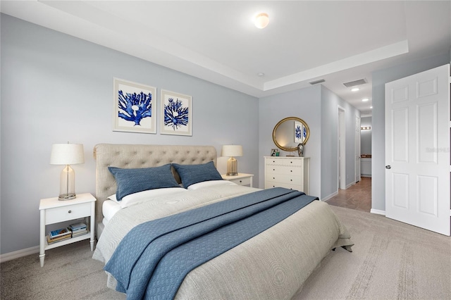 carpeted bedroom with a tray ceiling, visible vents, and baseboards