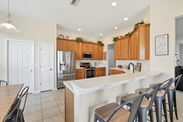 kitchen with brown cabinetry, visible vents, a peninsula, and stainless steel appliances