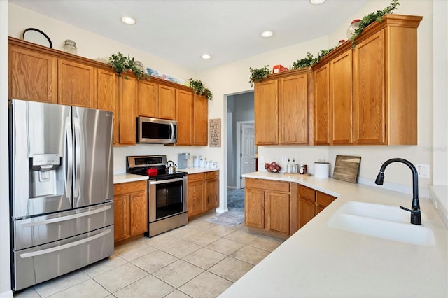 kitchen featuring brown cabinets, stainless steel appliances, light countertops, and a sink