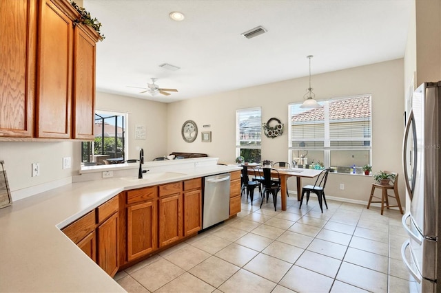 kitchen featuring brown cabinets, appliances with stainless steel finishes, a peninsula, and a sink