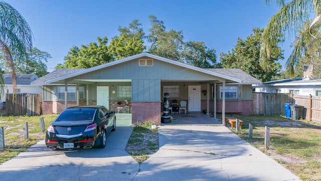 view of front of home featuring an attached carport, fence, brick siding, and driveway