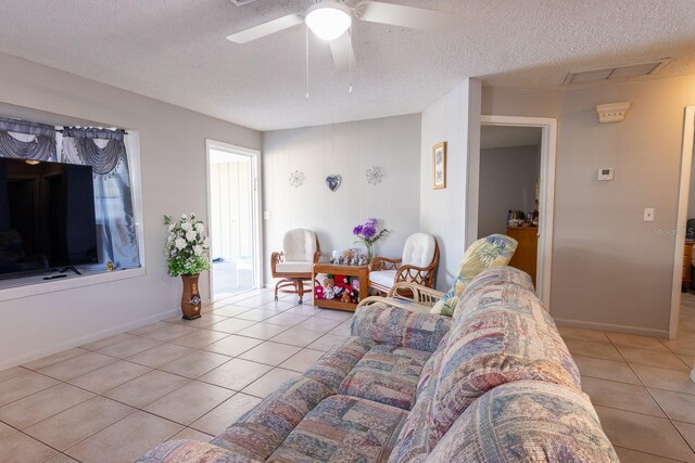 living area featuring light tile patterned floors, baseboards, a textured ceiling, and a ceiling fan