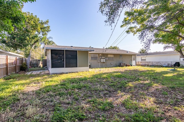 back of property with a yard, a fenced backyard, and a sunroom