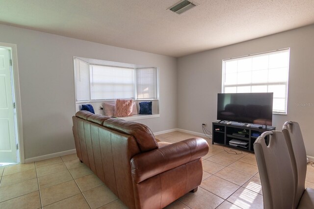 living room featuring light tile patterned floors, baseboards, and visible vents