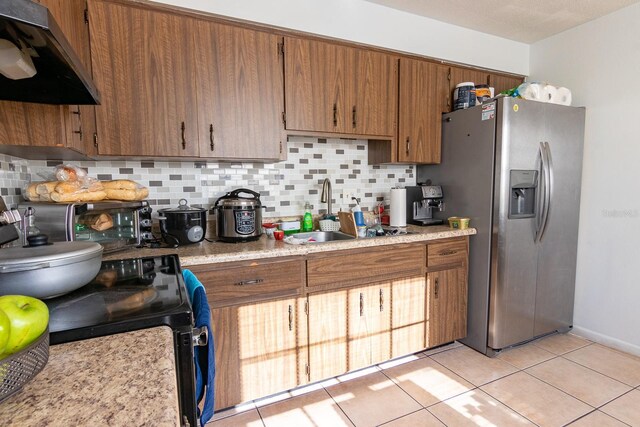 kitchen featuring range hood, light tile patterned floors, stainless steel fridge with ice dispenser, a sink, and tasteful backsplash