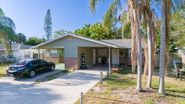 ranch-style house with brick siding, concrete driveway, a carport, and a shingled roof