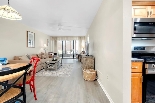 living area featuring baseboards, wood finished floors, and ceiling fan