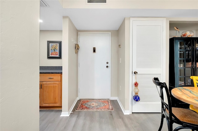 foyer entrance with light wood-style flooring, visible vents, and baseboards