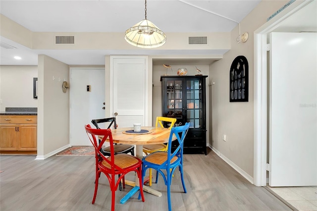 dining area with baseboards, visible vents, and light wood finished floors