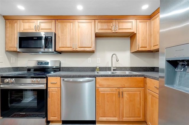 kitchen with a sink, dark countertops, appliances with stainless steel finishes, and recessed lighting