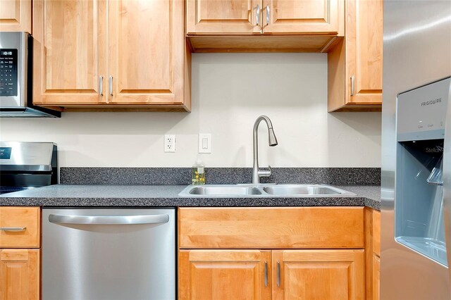 kitchen with dark countertops, appliances with stainless steel finishes, and a sink