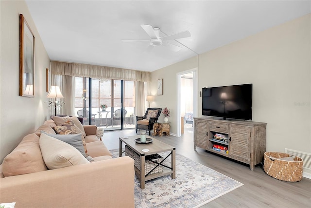 living room featuring visible vents, wood finished floors, and a ceiling fan