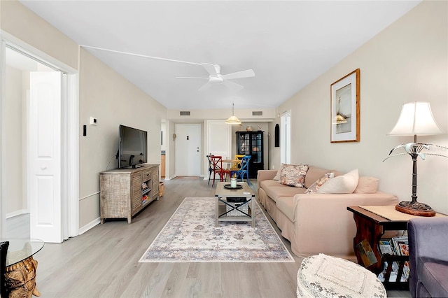 living area with visible vents, baseboards, light wood-style floors, and ceiling fan