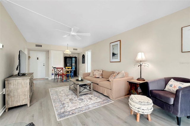 living room featuring visible vents, baseboards, light wood-style floors, and ceiling fan