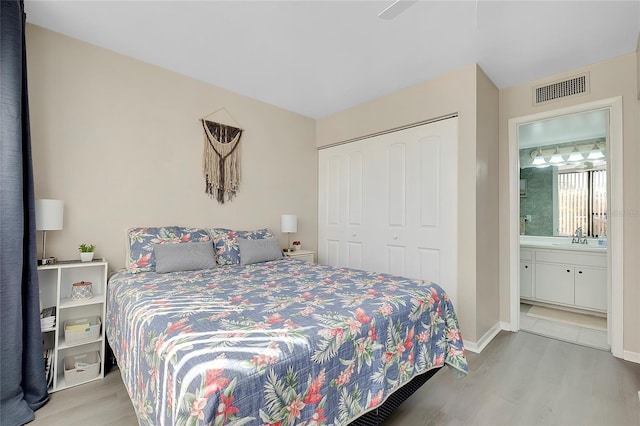 bedroom featuring a closet, visible vents, a sink, and wood finished floors