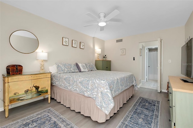 bedroom featuring ceiling fan, visible vents, baseboards, and wood finished floors