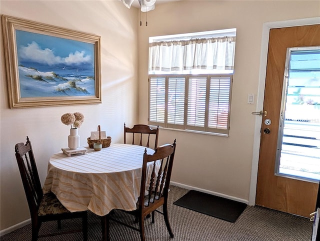 carpeted dining room featuring a ceiling fan, a healthy amount of sunlight, and baseboards