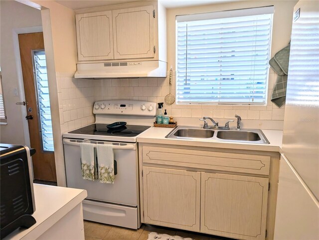 kitchen with tasteful backsplash, under cabinet range hood, light countertops, white appliances, and a sink