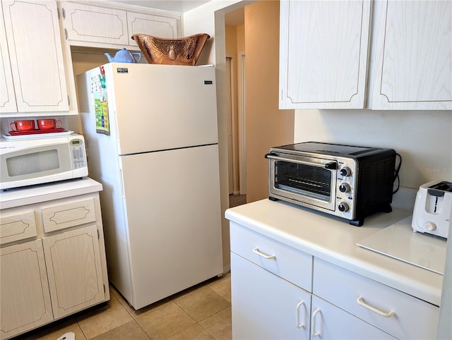 kitchen featuring white appliances, light tile patterned flooring, a toaster, and light countertops