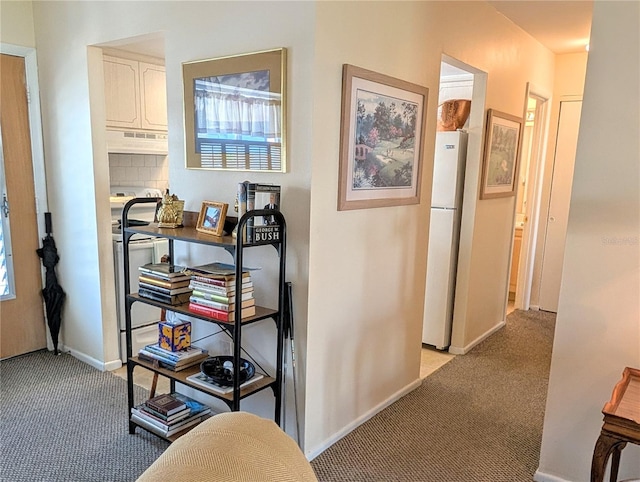 hallway with baseboards and light carpet