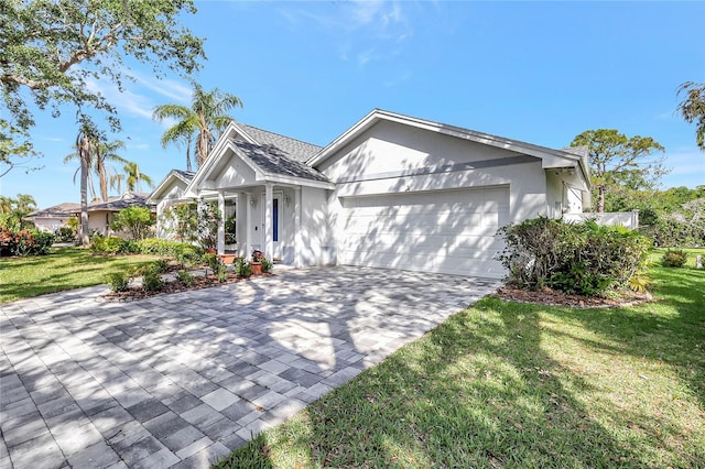 single story home featuring stucco siding, a front lawn, decorative driveway, and a garage