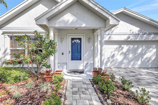 property entrance featuring a garage, driveway, and stucco siding