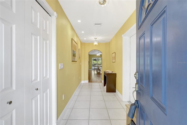 corridor featuring arched walkways, baseboards, visible vents, recessed lighting, and light tile patterned floors