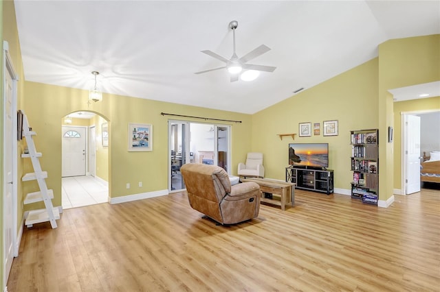 living area with arched walkways, light wood-style floors, a ceiling fan, and baseboards