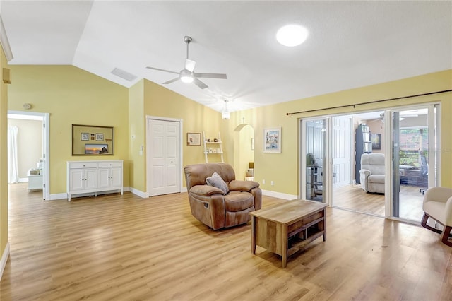 living room with arched walkways, light wood-type flooring, vaulted ceiling, visible vents, and a ceiling fan