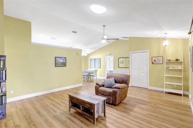 living area with vaulted ceiling, a ceiling fan, light wood-type flooring, baseboards, and visible vents