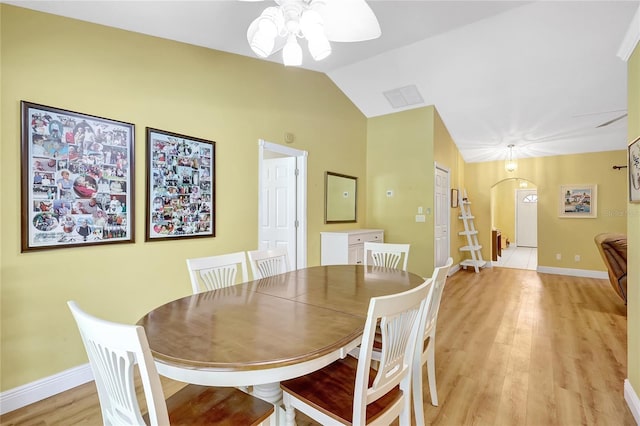 dining area featuring arched walkways, light wood-type flooring, vaulted ceiling, baseboards, and a ceiling fan