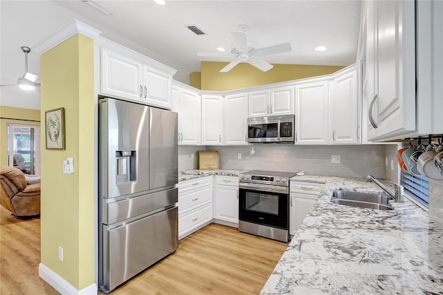kitchen featuring a ceiling fan, a sink, light wood-type flooring, stainless steel appliances, and white cabinetry