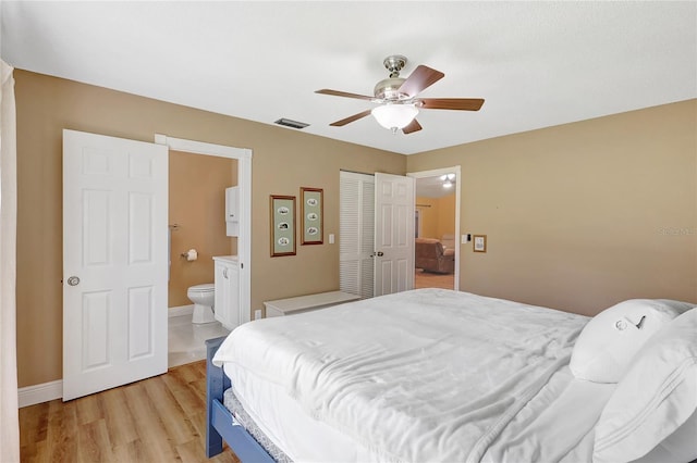 bedroom with a closet, light wood-style floors, ensuite bath, baseboards, and visible vents