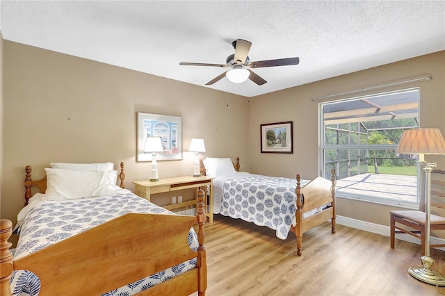 bedroom with baseboards, a ceiling fan, a textured ceiling, and light wood finished floors
