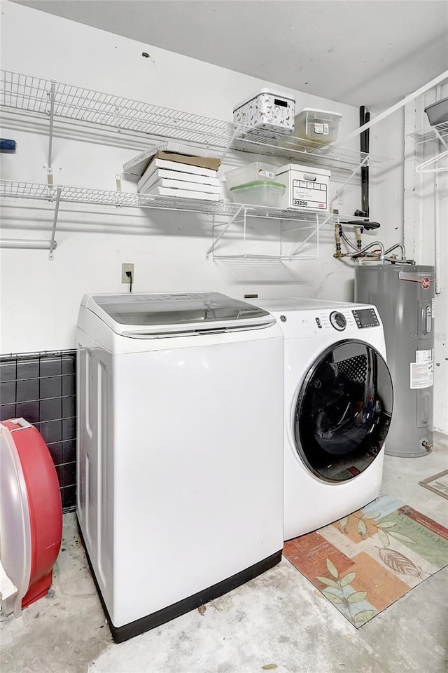 washroom featuring water heater, washer and dryer, and laundry area