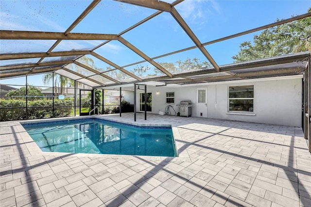 outdoor pool featuring glass enclosure and a patio area
