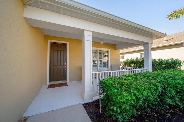 view of exterior entry with stucco siding and a porch