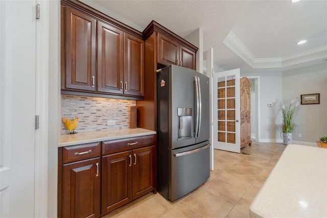 kitchen with decorative backsplash, light countertops, stainless steel fridge with ice dispenser, and a raised ceiling