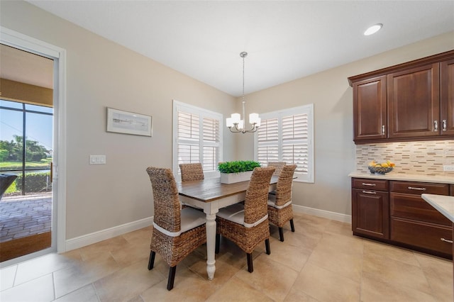 dining area with light tile patterned floors, baseboards, a wealth of natural light, and a chandelier