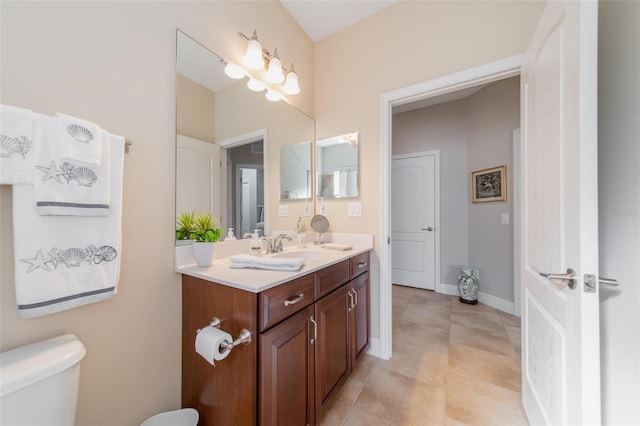 bathroom with baseboards, toilet, vanity, and tile patterned flooring