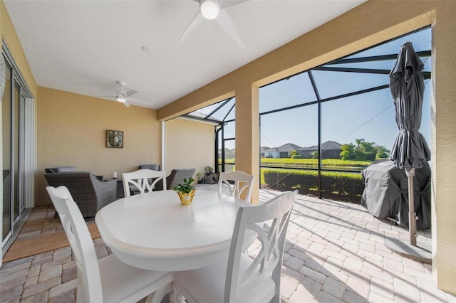 view of patio with a lanai, a ceiling fan, and outdoor dining space