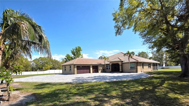 ranch-style home with stucco siding, an attached garage, a front lawn, and fence